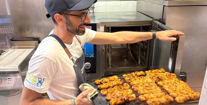 Chef estrae spiedini di pesce alla griglia da un forno professionale in cucina.