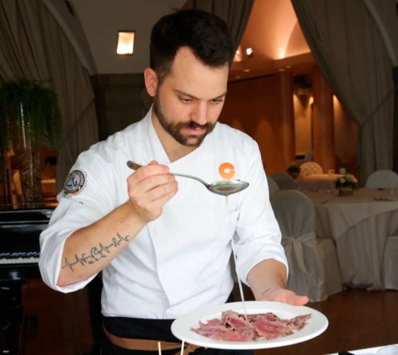 Chef versa salsa su fette di roast beef durante l’impiattamento.