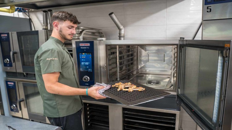 Chef estrae pollo grigliato da un RATIONAL iCombi Pro forno professionale in una cucina professionale.