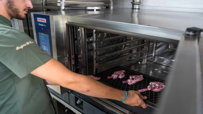 Chef inserisce costolette di agnello in un RATIONAL iCombi Pro forno professionale in cucina.