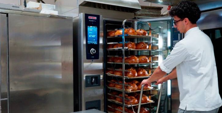 Pasticcere estrae carrello con dolci dal RATIONAL iCombi Pro forno professionale.