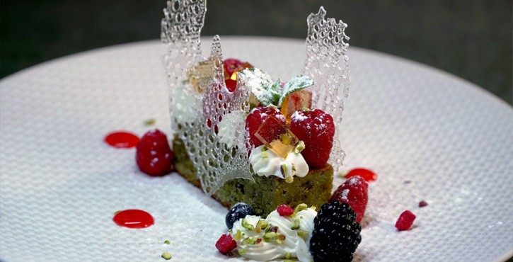 Dessert elegante con frutti di bosco, crema e decorazione di zucchero in stile gourmet.