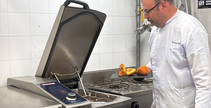 Chef controlla arancini fritti accanto al sistema di cottura RATIONAL iVario in cucina professionale.