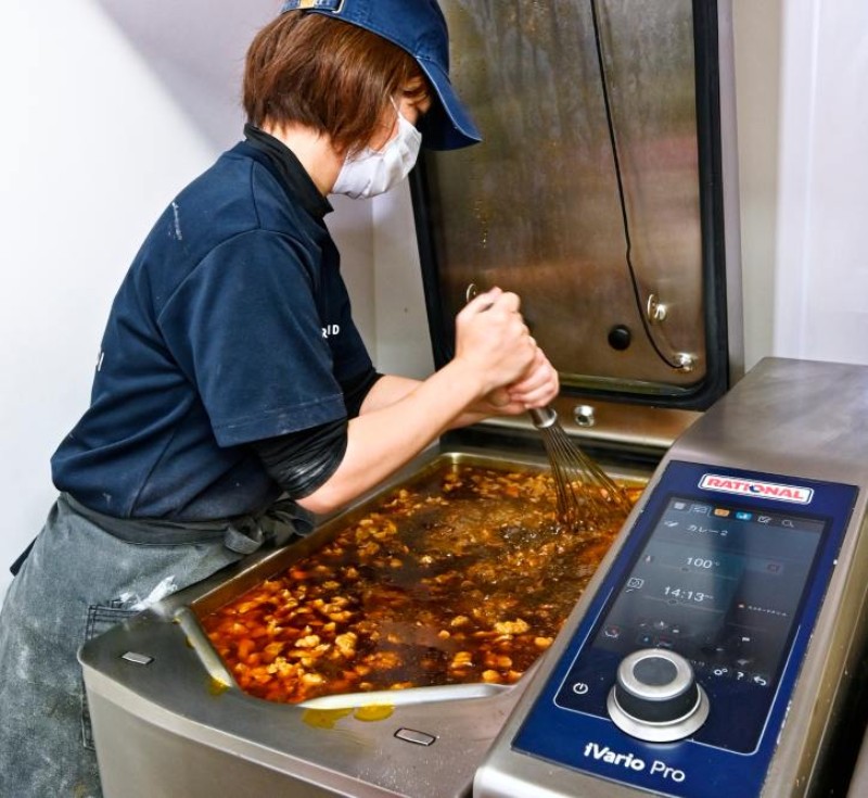 業務用キッチンでRATIONAL iVario Proのパンでシチューをかき混ぜるシェフ。