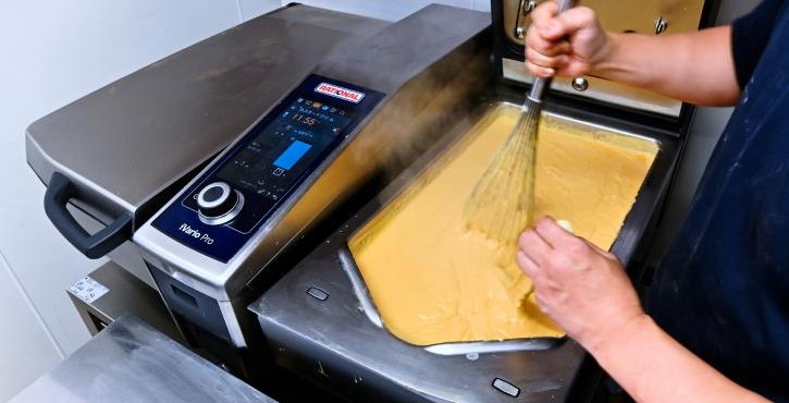 ベーカリーでRATIONAL iVario Proのパンでカスタードを泡立てる職人。