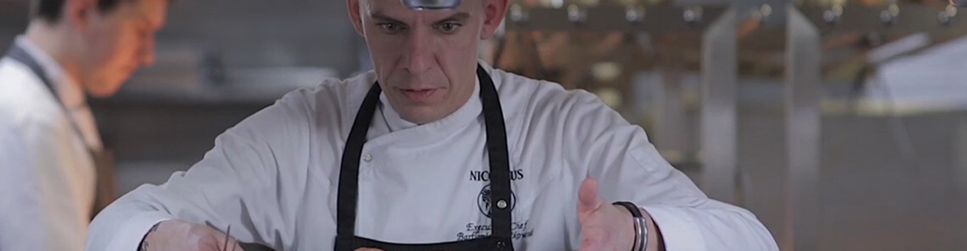 Szef kuchni w bialym fartuchu starannie wykancza danie w profesjonalnej kuchni restauracyjnej.