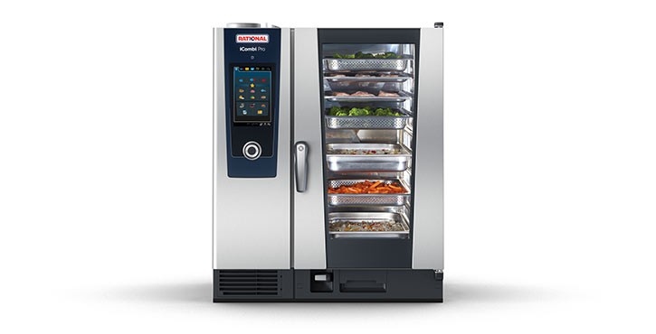 An iCombi Pro stands alone on a plain background, with a full load of gastros steaming inside, each with different ingredient on each shelf, such as vegetables, rice, whole fish and salmon