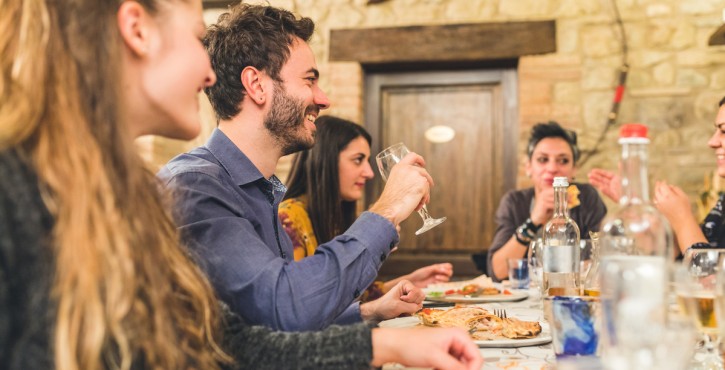 Groupe d’amis partageant une pizza et des boissons dans un restaurant chaleureux.