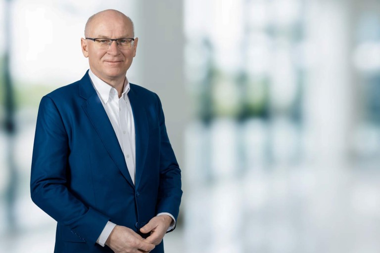 Geschäftsmann im blauen Anzug steht in heller, moderner Bürohalle.