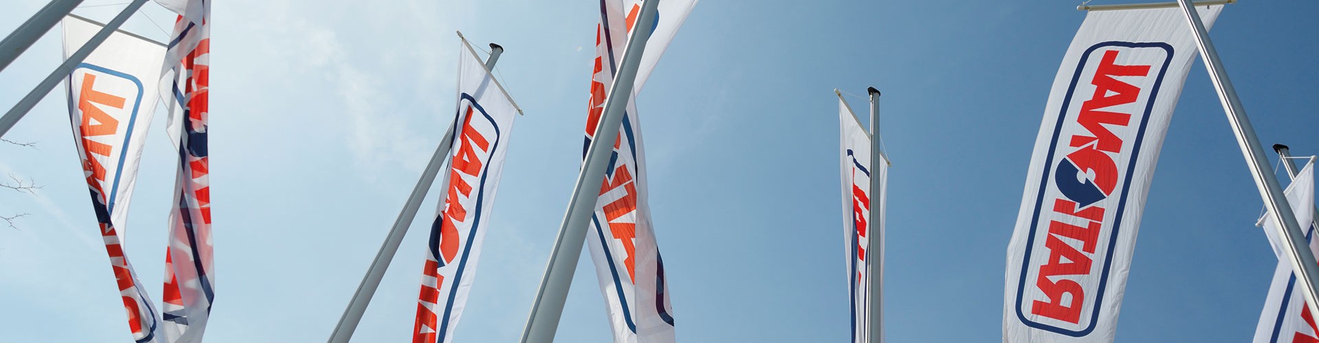 Multiple flags with "Rational" logo flying on poles against a blue sky.