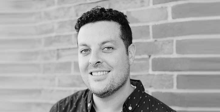 Black-and-white portrait of Andrew Martino in front of a brick wall.