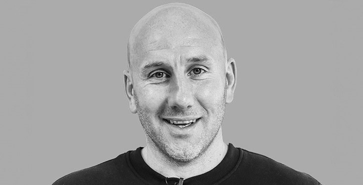 Portrait photo of Andrew Maxwell smiling warmly at the camera.