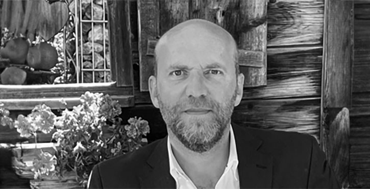 Black and white portrait of Carsten Vesper wearing glasses and smiling warmly.