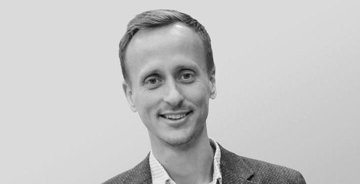 A man in a suit smiling warmly at the camera.