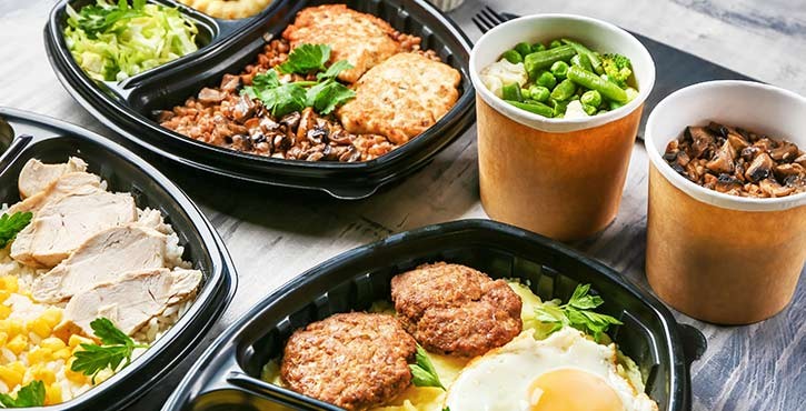 Prepared meal containers with diverse dishes and side salads.
