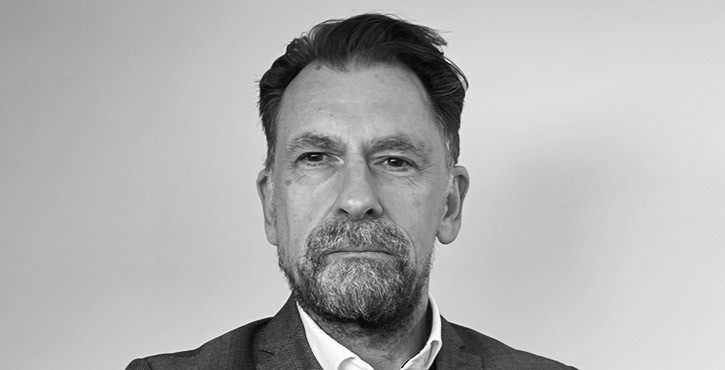 Portrait of a man with a serious expression and a beard wearing a suit.