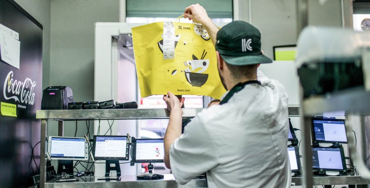  A Keatz employee hands over a yellow bag with an order in a modern kitchen.