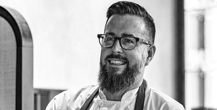 Jeff Kipp smiling, wearing glasses and a chef's uniform.