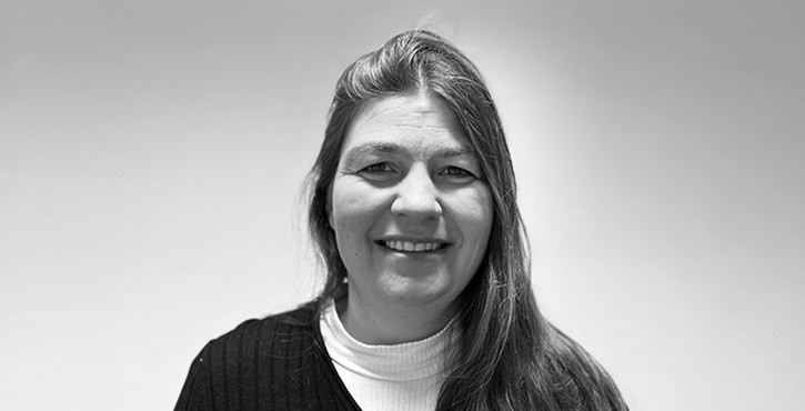 Black and white portrait photo of a smiling woman with long hair and a dark jumper.