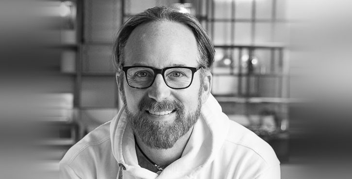  Portrait photo of a man with glasses, a beard, and a friendly smile.