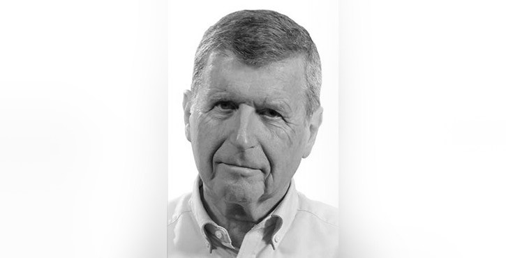 Portrait of an elderly man with short grey hair, wearing a light shirt.