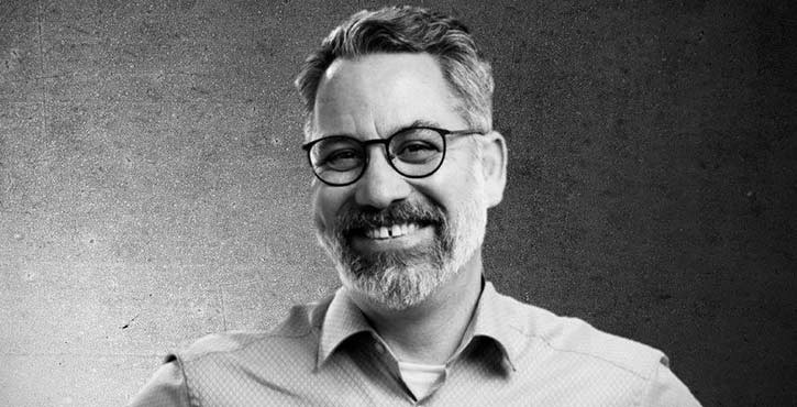 Black and white portrait of Stephan Leuschner with a beard and glasses, slightly smiling.