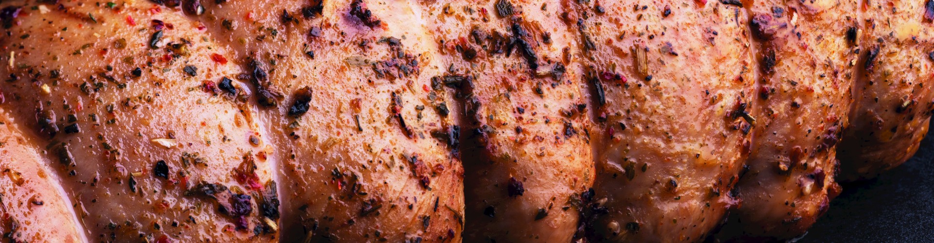 Primo piano di un arrosto di tacchino stagionato, che mette in evidenza le spezie e la consistenza della superficie.