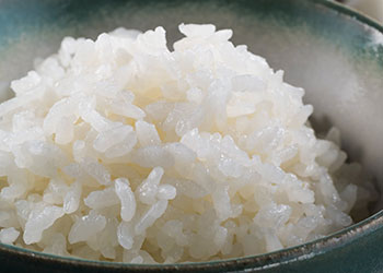 A close-up of fluffy, white basmati rice served in a green bowl.