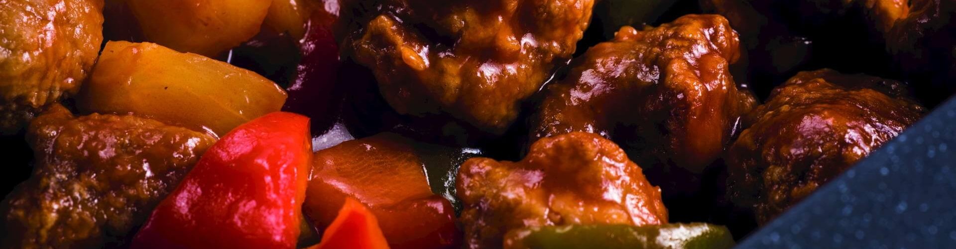 糖醋肉特写,鲜嫩的肉丸与甜椒和菠萝混合在浓郁的酱汁中。