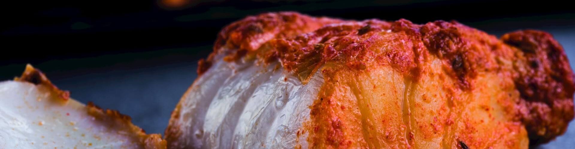 A close-up of tawa fish, showcasing perfectly cooked, spiced fillets with a crispy outer layer, served on a black surface.