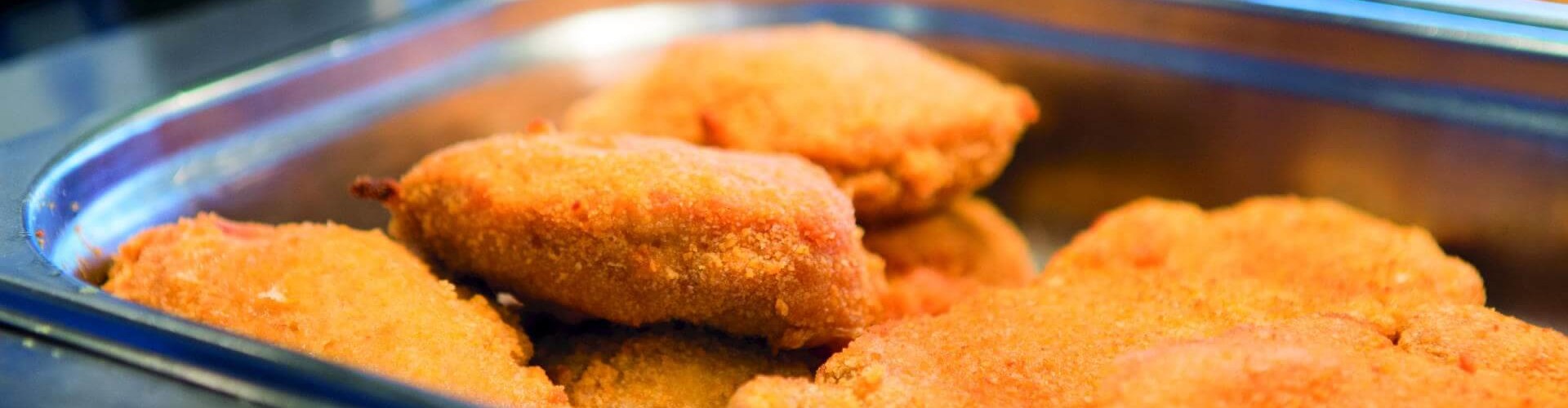 Filets de poisson panés dans un plateau métallique, dorés et fraîchement cuits