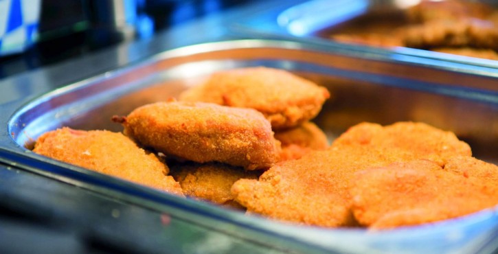 Filets de poisson panés dans un plateau métallique, dorés et fraîchement cuits