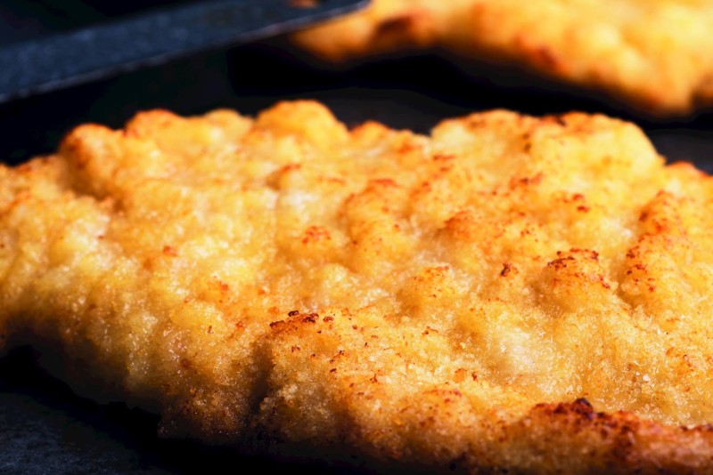 Filet de poisson pané croustillant avec une croûte dorée, gros plan montrant la texture détaillée de l'enrobage croustillant