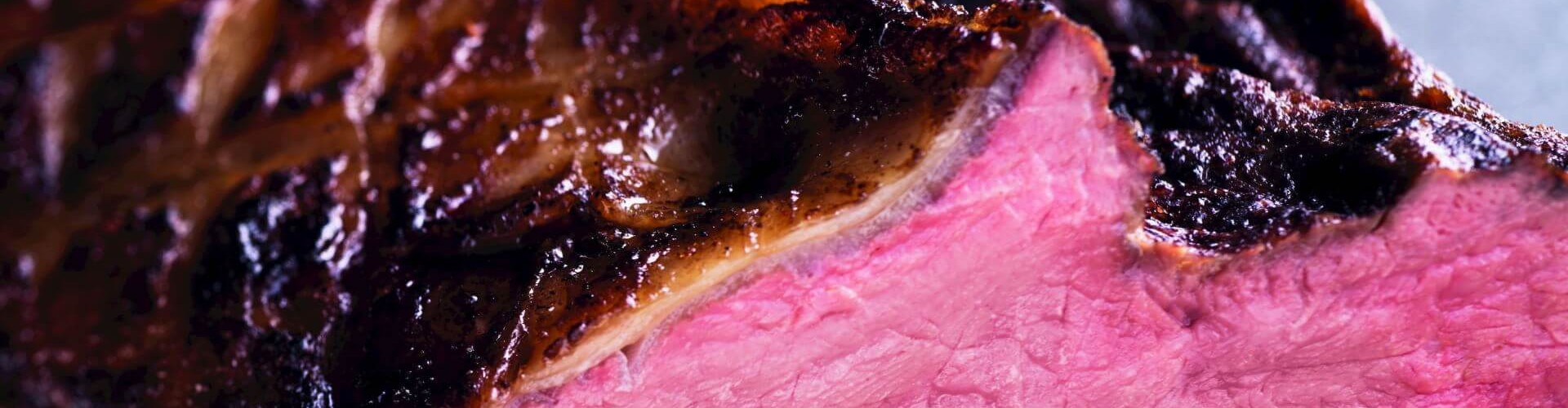 Eine Nahaufnahme einer perfekt gegarten Roastbeef-Scheibe, die ihr pinkes, saftiges Inneres und eine gebräunte, knusprige Kruste zeigt.