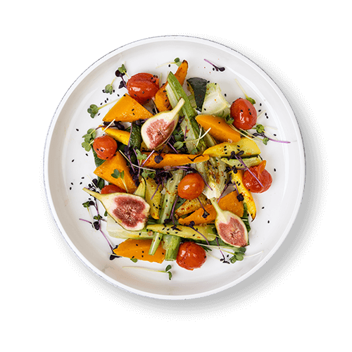 Plate of grilled vegetables topped with cherry tomatoes and fresh figs.