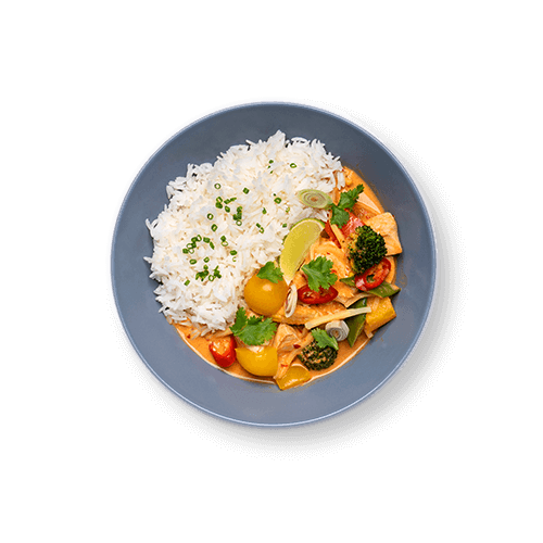 Plate of rice served with colorful curry vegetables and garnished with lime and herbs.