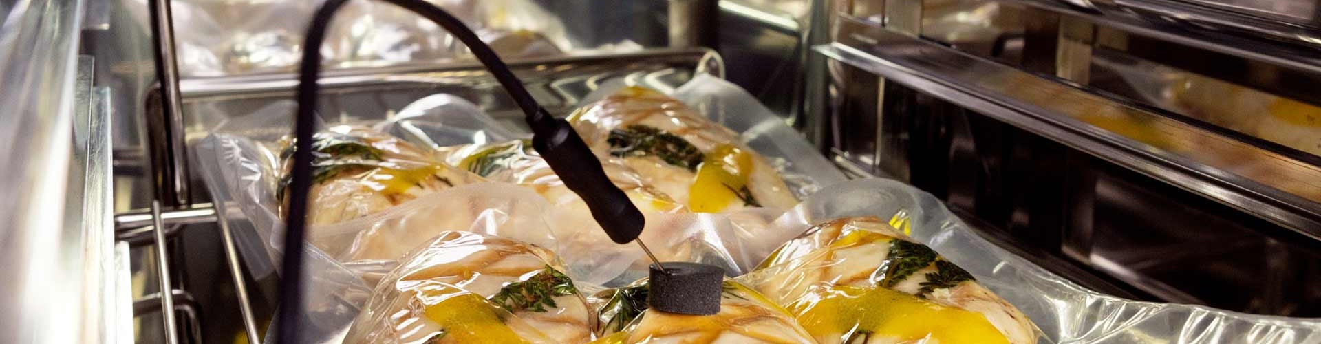 Bolsas de alimentos al vacío en un horno combi para cocinar al vacío, con un termómetro insertado.