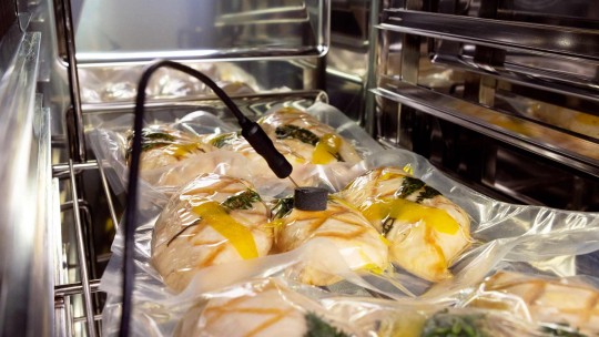 Sacchetti di cibo sigillati sottovuoto in un forno combinato per la cottura sous-vide, con una sonda di temperatura inserita.