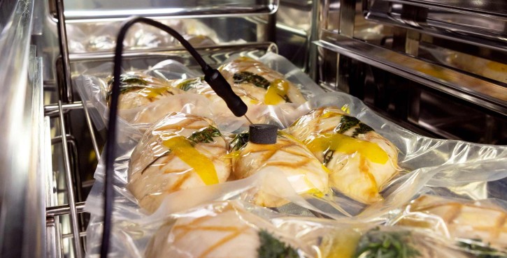 Sacs d'aliments scellés sous vide dans un four mixte pour la cuisson sous vide, avec une sonde de température insérée.
