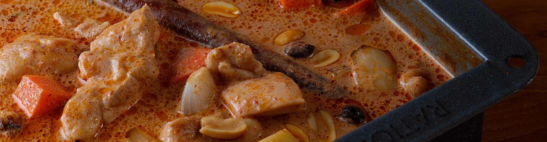 A rich and creamy Thai curry with chicken, vegetables, and spices simmering in a pot.