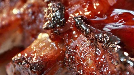 Close-up of juicy ribs glazed with barbecue sauce, showcasing a caramelized texture.