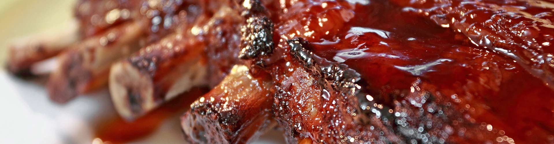 Primo piano di costine di ricambio succose e glassate con salsa BBQ lucida.