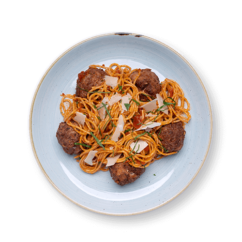 Plate of spaghetti topped with meatballs and garnished with cheese and herbs.