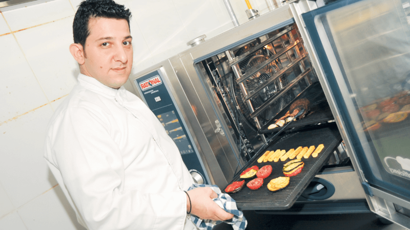 Chef placing grilled vegetables in a Rational combi oven.