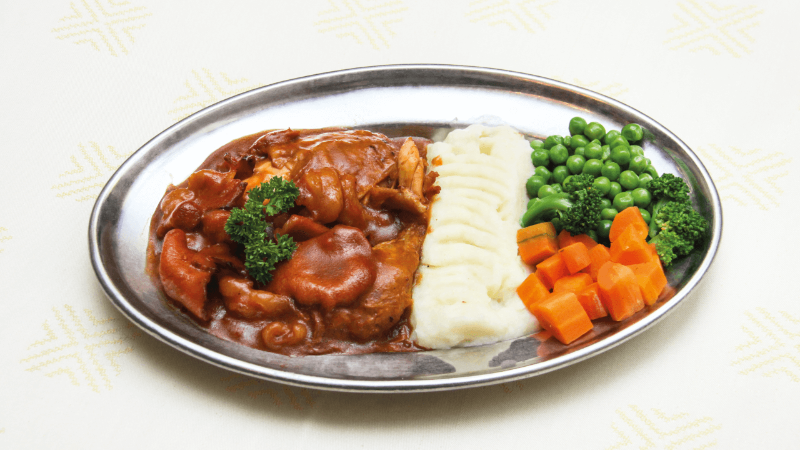 A plate with mashed potatoes, vegetables (broccoli, carrots, peas), and a portion of meat with gravy.
