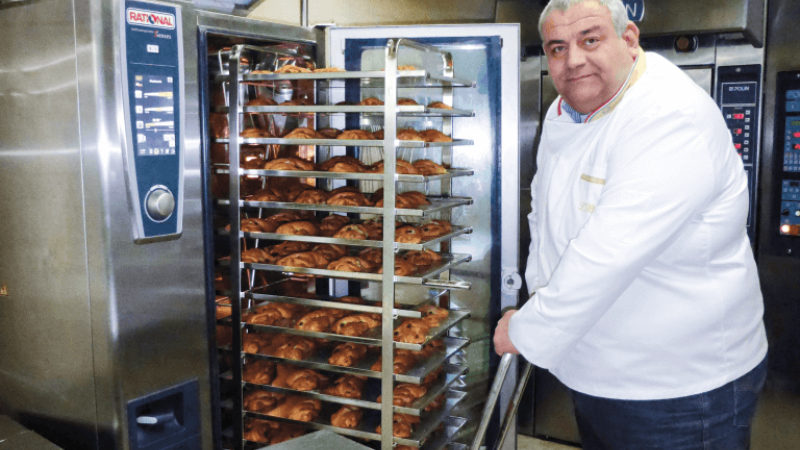 Chef operating a Rational oven, taking out freshly baked pastries from the oven racks.