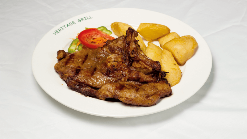 A plate of grilled steak served with roasted potatoes and a side of fresh salad, including tomato, cucumber, and carrots.