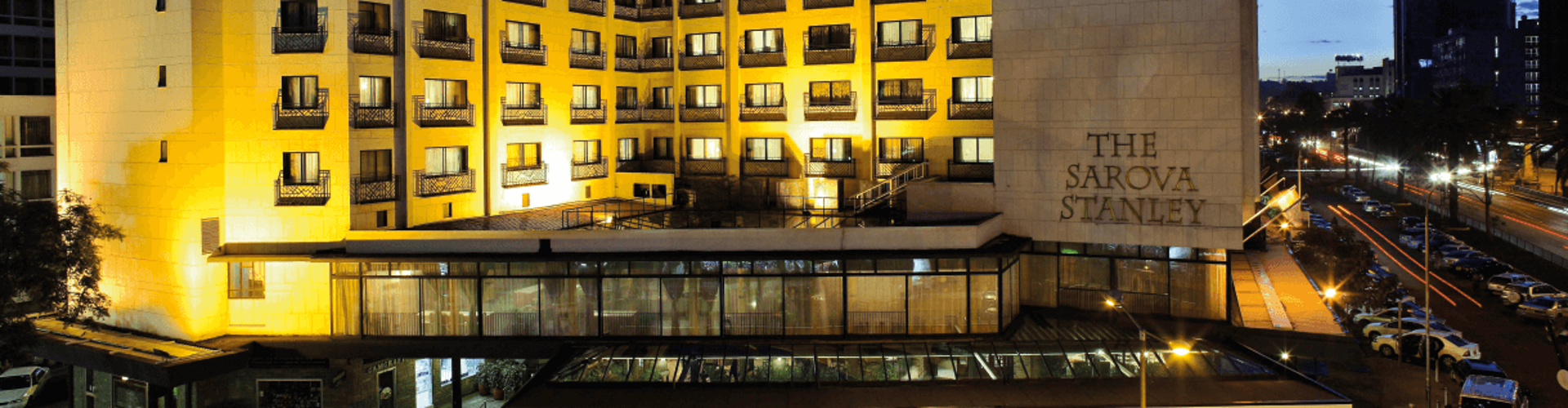 The Sarova Stanley hotel illuminated at night with a cityscape in the background.