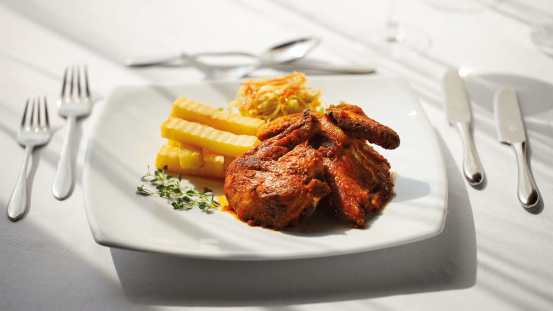 Plate of grilled chicken, crinkle-cut fries, and coleslaw on a white tablecloth.