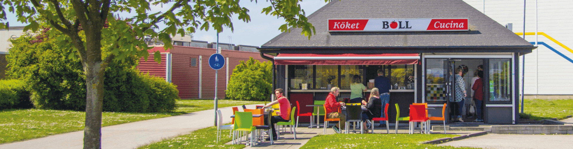 A vibrant outdoor dining area at the BÖLL kitchen, featuring colorful chairs and a cozy atmosphere on a sunny day.